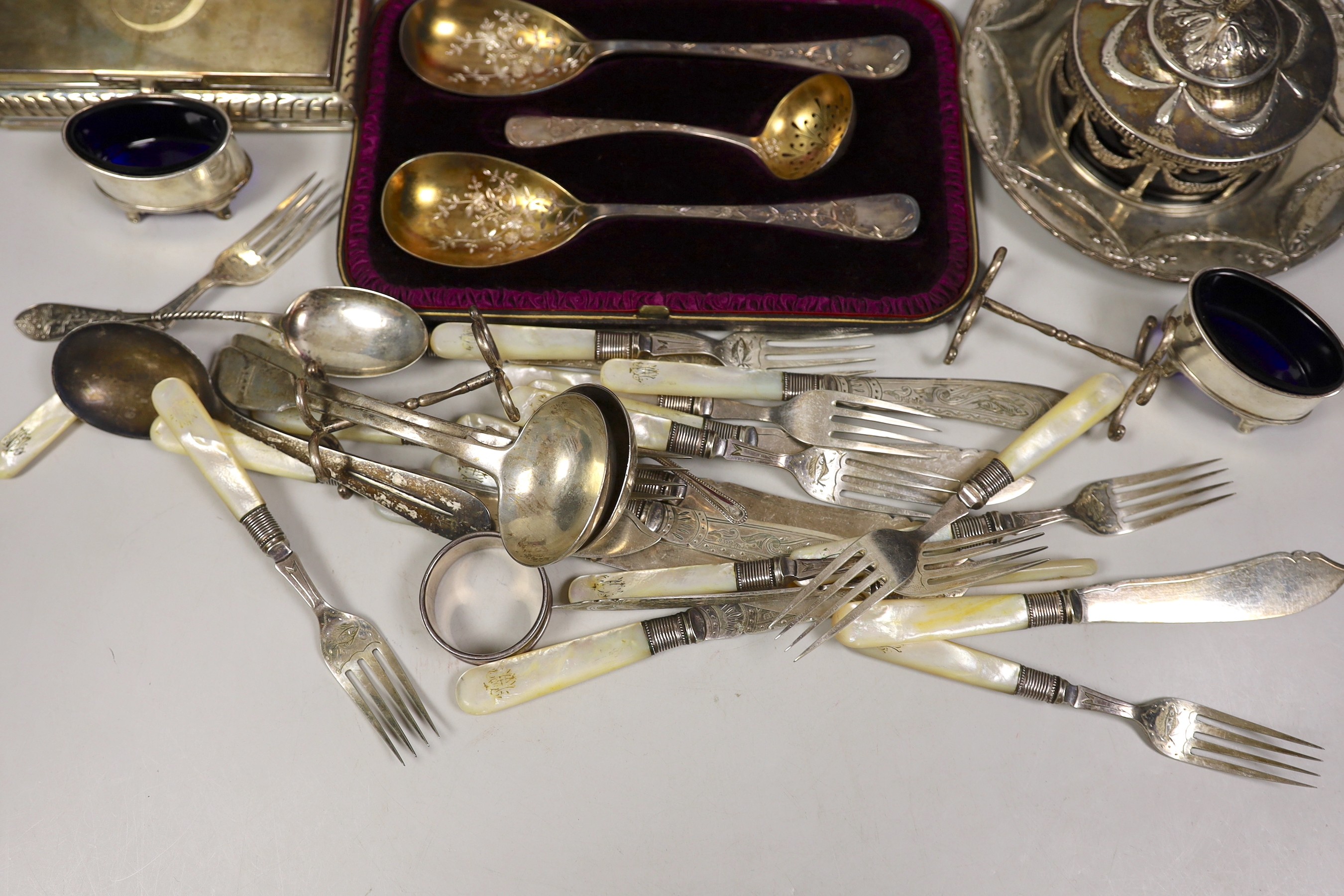 A late 19th century Hanau white metal butter dish stand, with blue glass liner, diameter 18.3cm, a sterling mounted cigarette box, a cased Victorian three piece silver cutlery dessert set, a pair of Victorian silver fidd